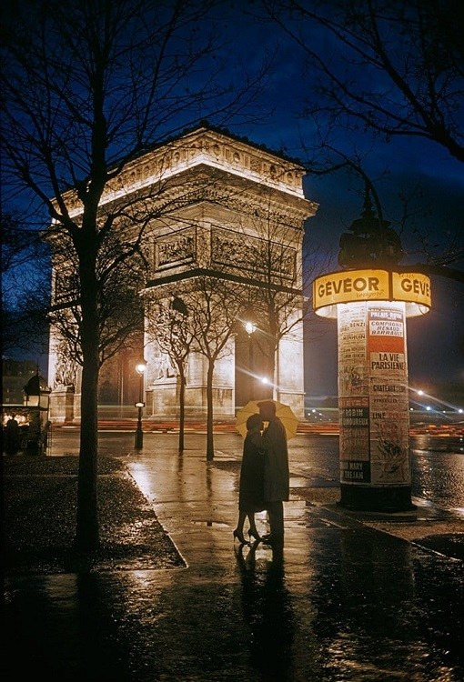 couple is standing next to the Arc de Triomphe