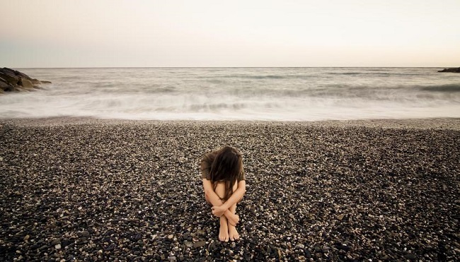 sad girl sitting at beach 